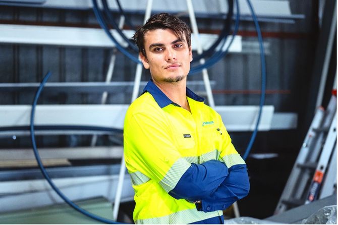 Worker in yellow safety jacket with arms crossed in an industrial setting