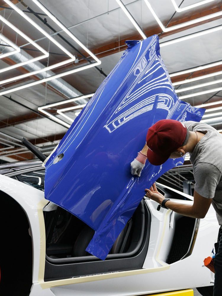 A man is working on a blue car in a garage