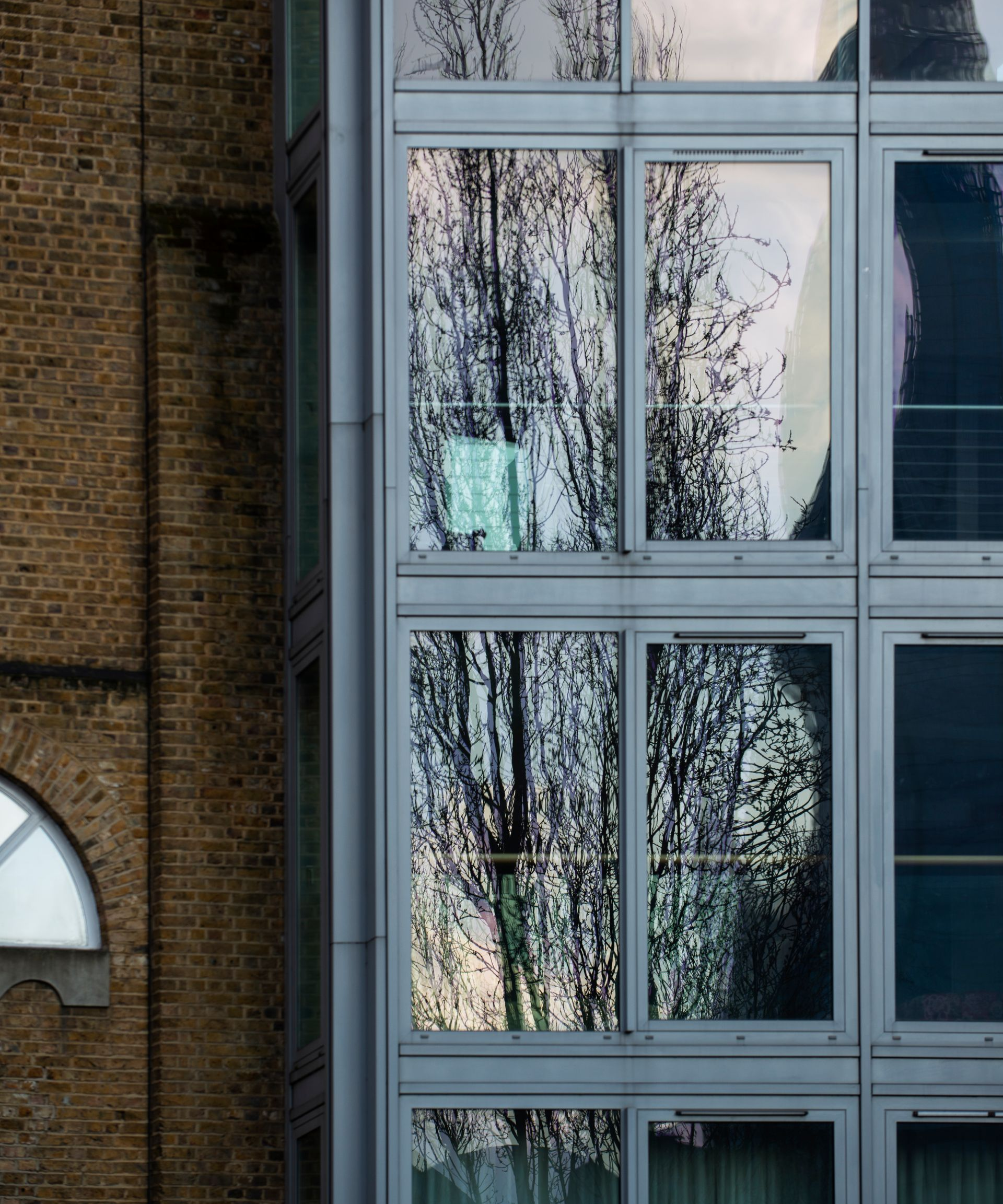 Modern building facade with large reflective windows and brick wall.
