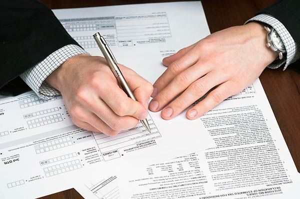 A person is writing on a piece of paper with a pen