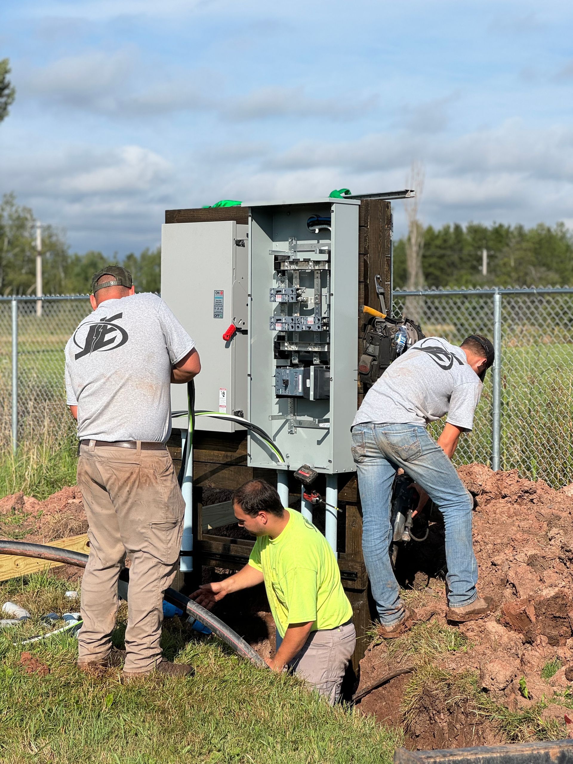 Electrician working on an open electrical panel with multiple wires inside a brick room