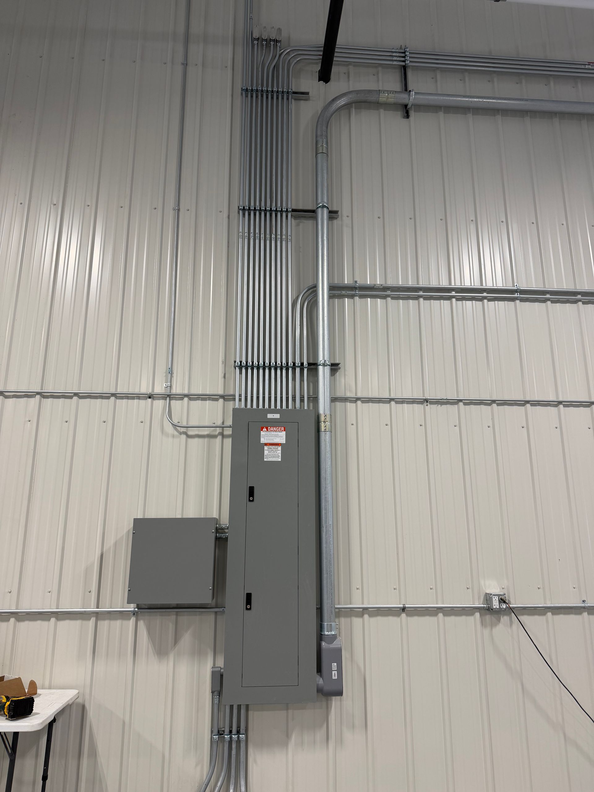 Gray electrical panel with conduit and wall-mounted box in an industrial interior Gray electrical panel with conduit and wall-mounted box in an industrial interior