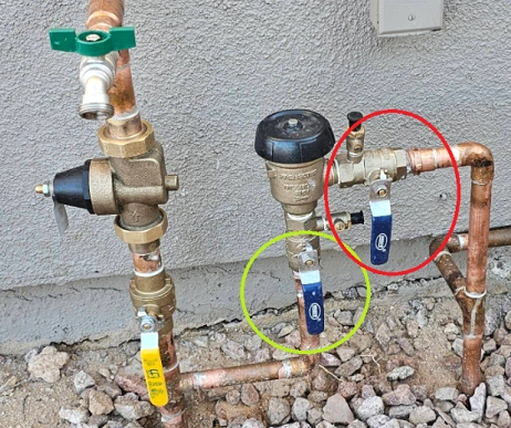Water pipes and valves outdoors with a green, yellow, and blue handle. Highlighted in red and yellow.
