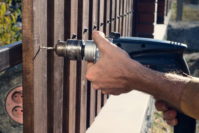 A Man is Using a Drill to Drill a Hole in a Wooden Fence — Beerwah Co-Op in Beerwah, QLD