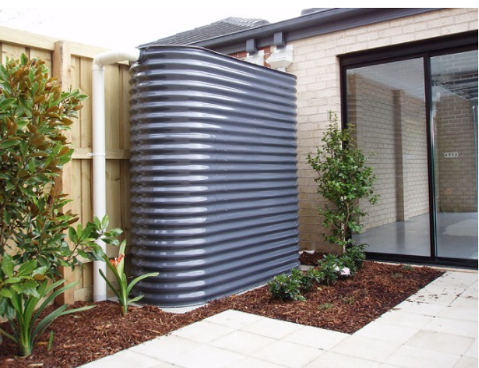 A gray water tank is in the backyard of a house