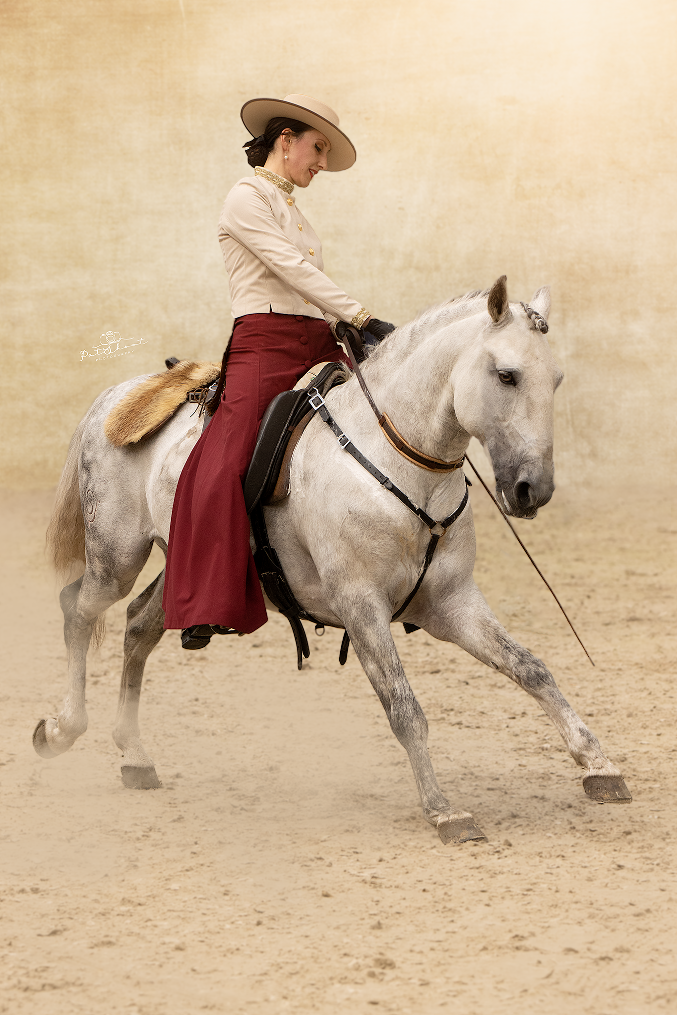 Vrouw te paard, gekleed in westernkleding, voert een rijmanoeuvre uit in een arena.