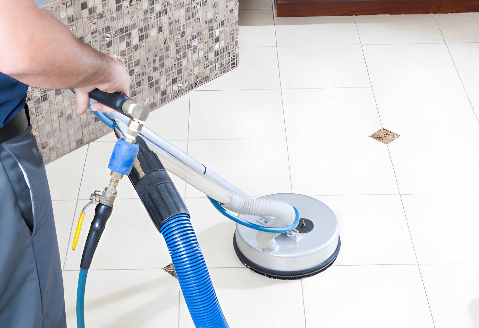 Vacuum hose cleaning a gray carpet beside a blue cubicle wall