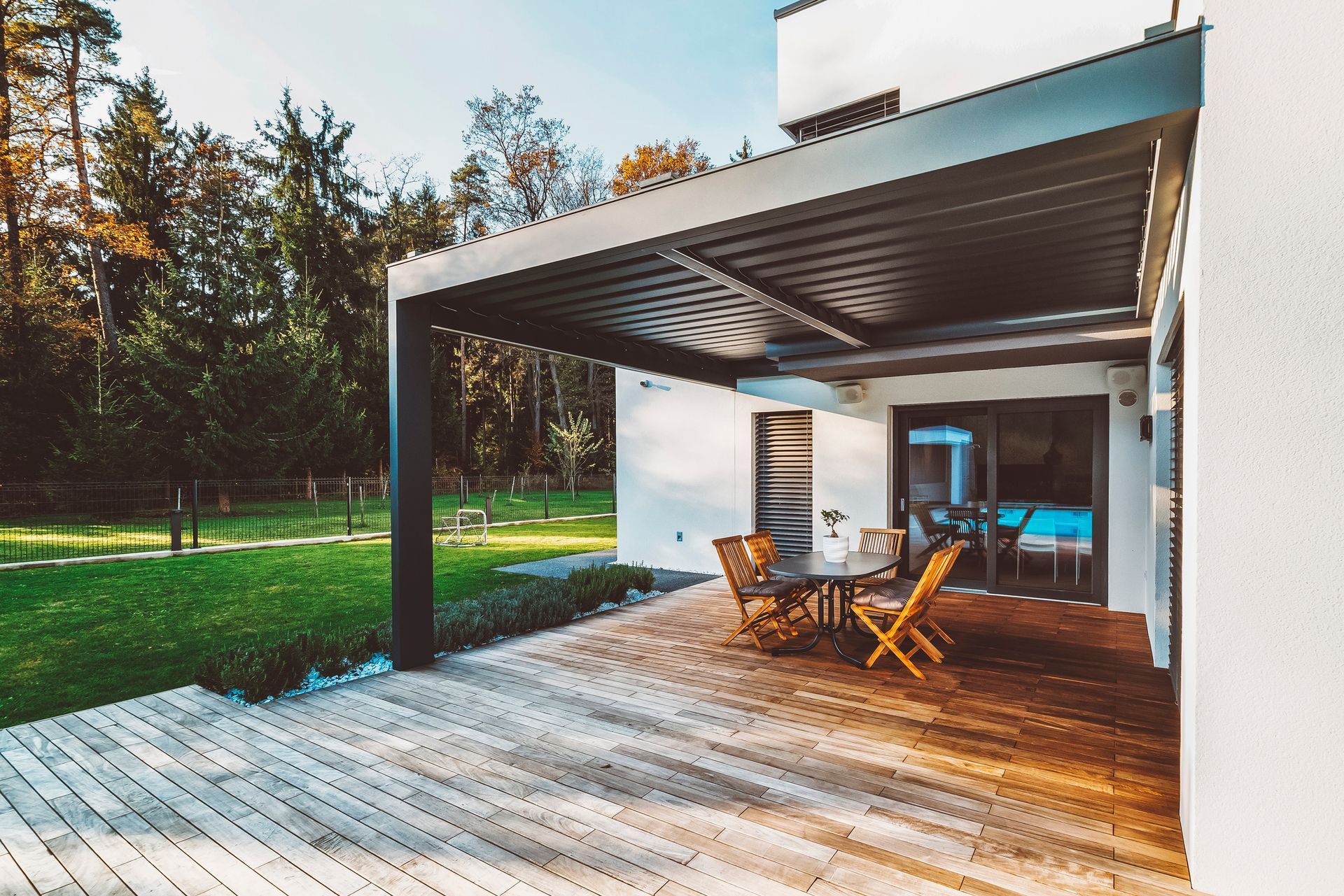 A wooden deck with a table and chairs under a pergola.