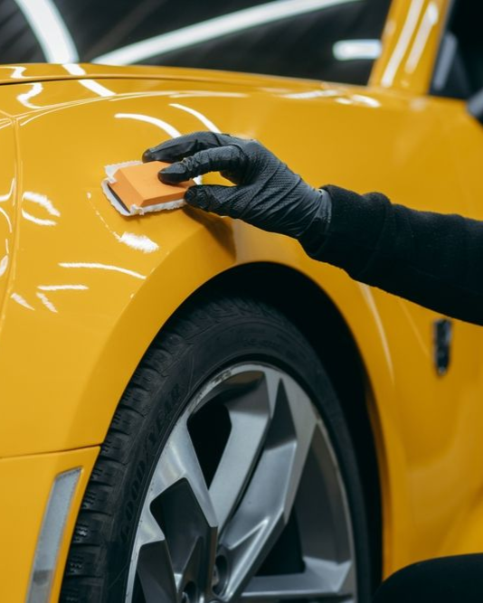 A person is applying a clear film to the hood of a car.