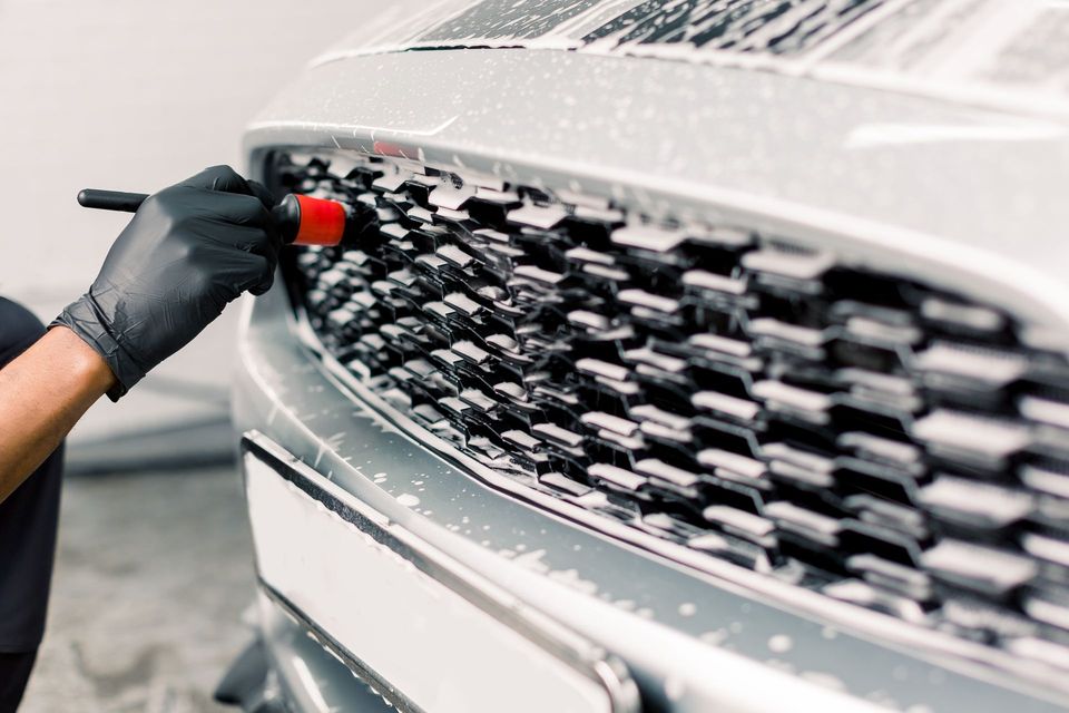 A car is being washed with foam in a garage.