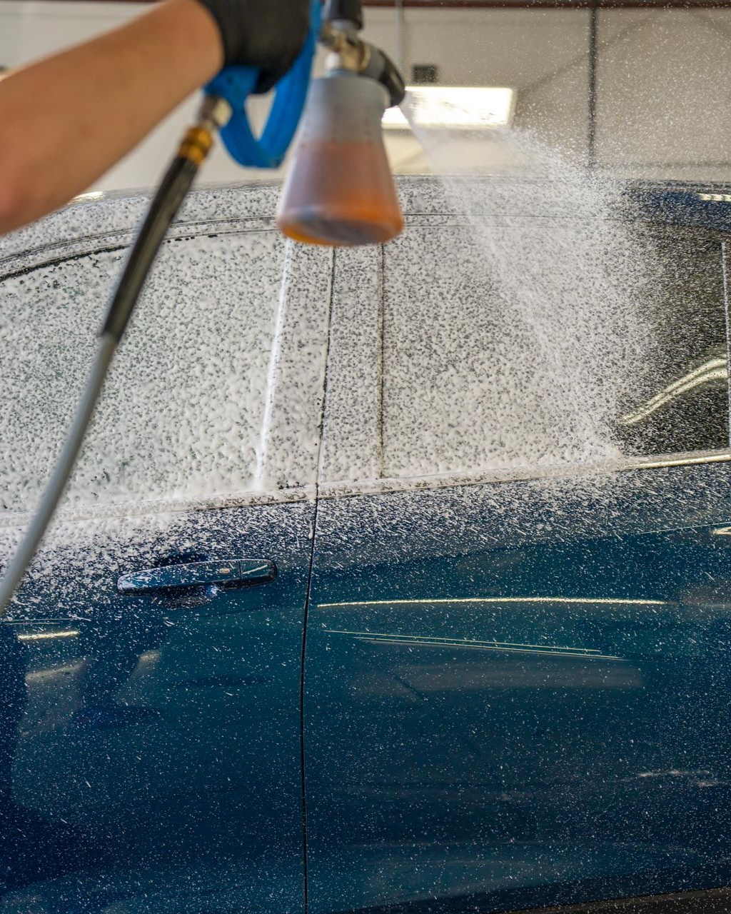 A car is covered in plastic wrap in a garage.