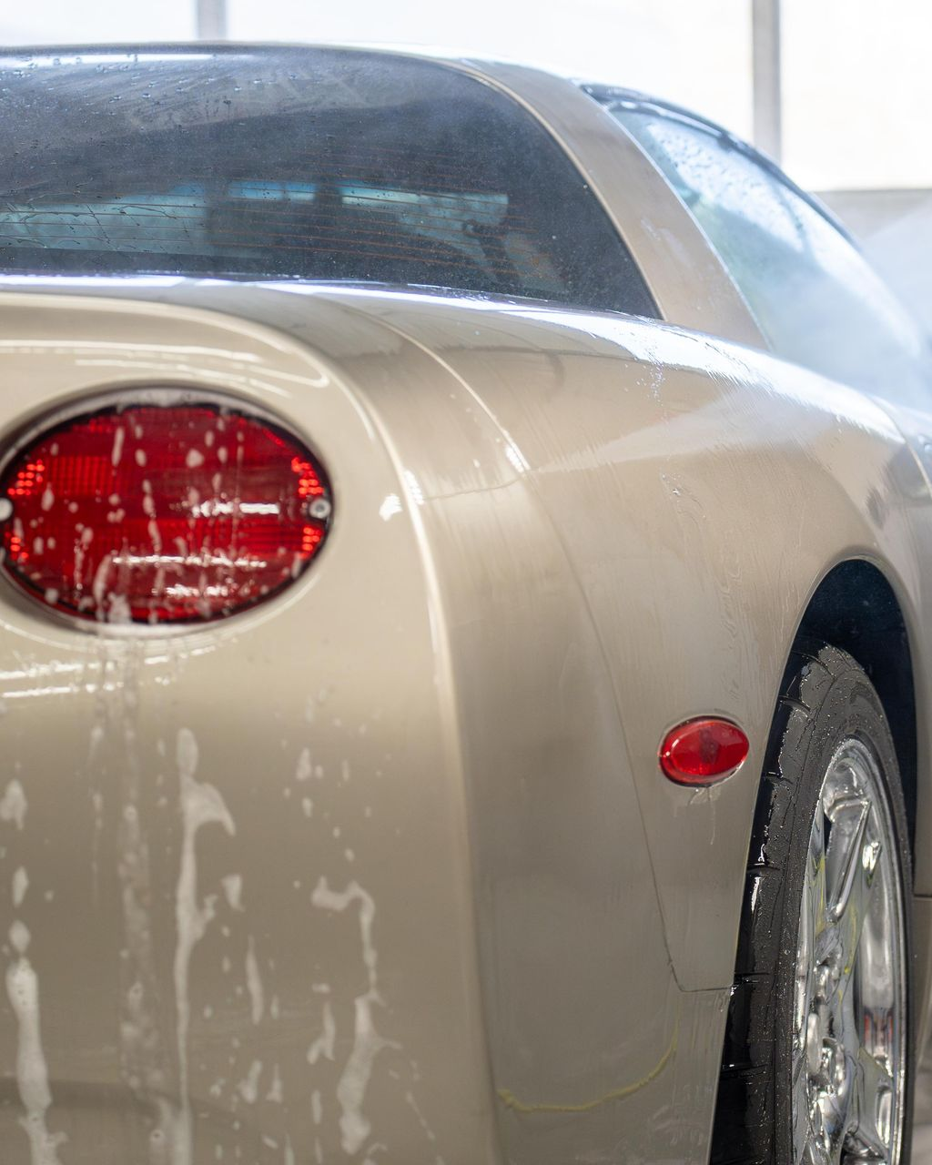 A person is washing a car wheel with foam