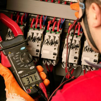 A man is holding a digital multimeter that reads 37.1 A man is holding a digital multimeter that reads 37.1