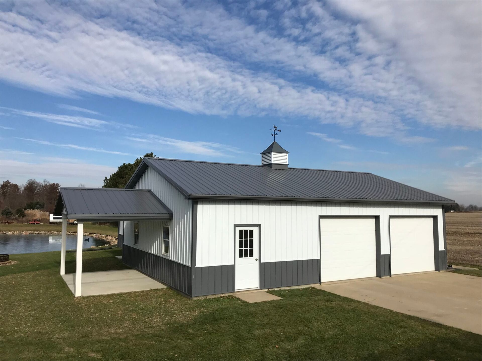 a white and gray garage with a gray roof and a porch.