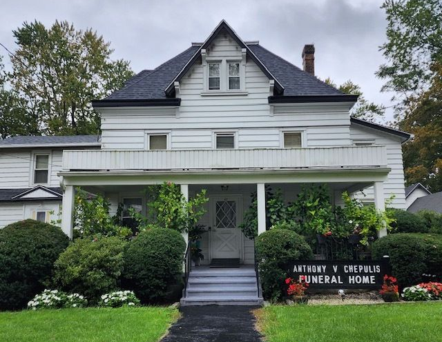 White funeral home with porch, steps, and sign reading “Arthur C. Cremin Funeral Home”