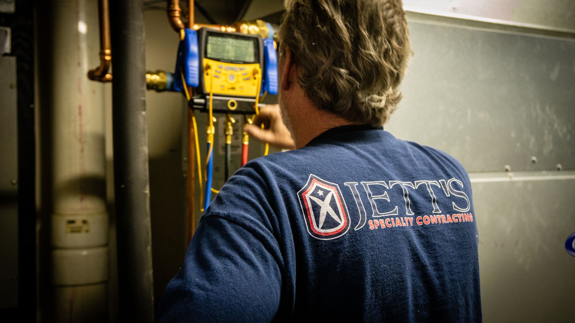 Technician using a wall-mounted digital gauge in an industrial setting