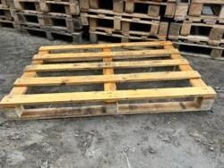 A wooden pallet is sitting on the ground next to a pile of wooden pallets.