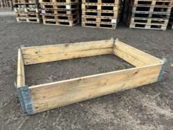 A wooden box is sitting on the ground next to pallets.