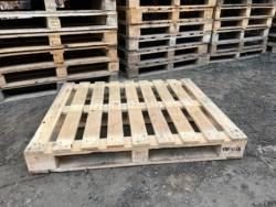 A wooden pallet is sitting in front of a pile of wooden pallets.
