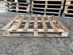 A wooden pallet is sitting on the ground next to a pile of wooden pallets.