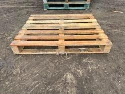 A wooden pallet is sitting on top of a dirt field.