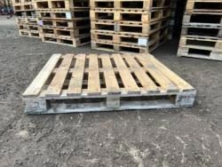 A wooden pallet is sitting on the ground next to a pile of wooden pallets.