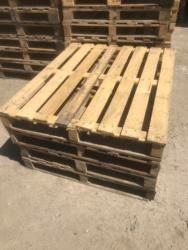 A stack of wooden pallets sitting on top of each other on a cement floor.