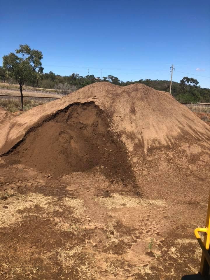 A Large Pile of Brown Soil on a Dry, Grassy Field Under a Blue Sky — The Caves Quarry CQ in The Caves, QLD