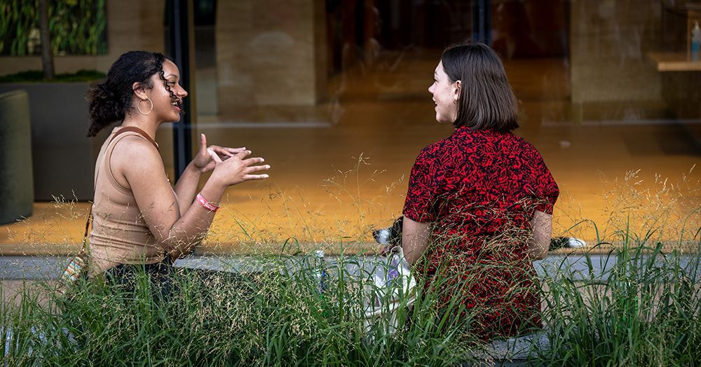 two women are sitting outside talking to each other at the 2023 Clayton Art Fair, Clayton, Missouri. 