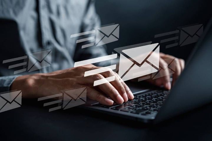 Un uomo sta scrivendo su un computer portatile da cui escono delle buste.