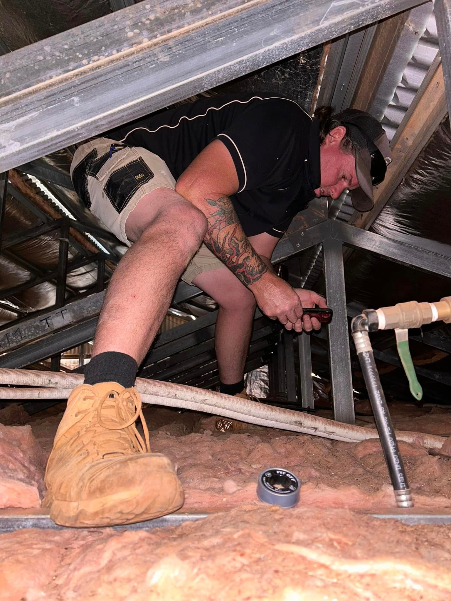 A Man Is Fixing A Pipe Underground — Araluen Plumbing In Braitling, NT
