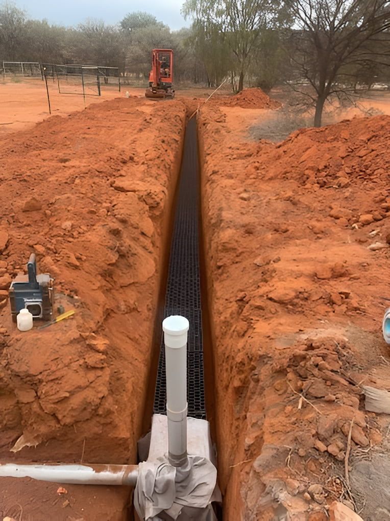 A Pipe Is Being Installed In A Trench In The Dirt — Araluen Plumbing In Braitling, NT