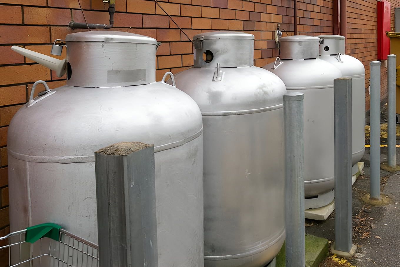 A Row Of Propane Tanks Are Lined Up In Front Of A Brick Wall — Araluen Plumbing In Braitling, NT