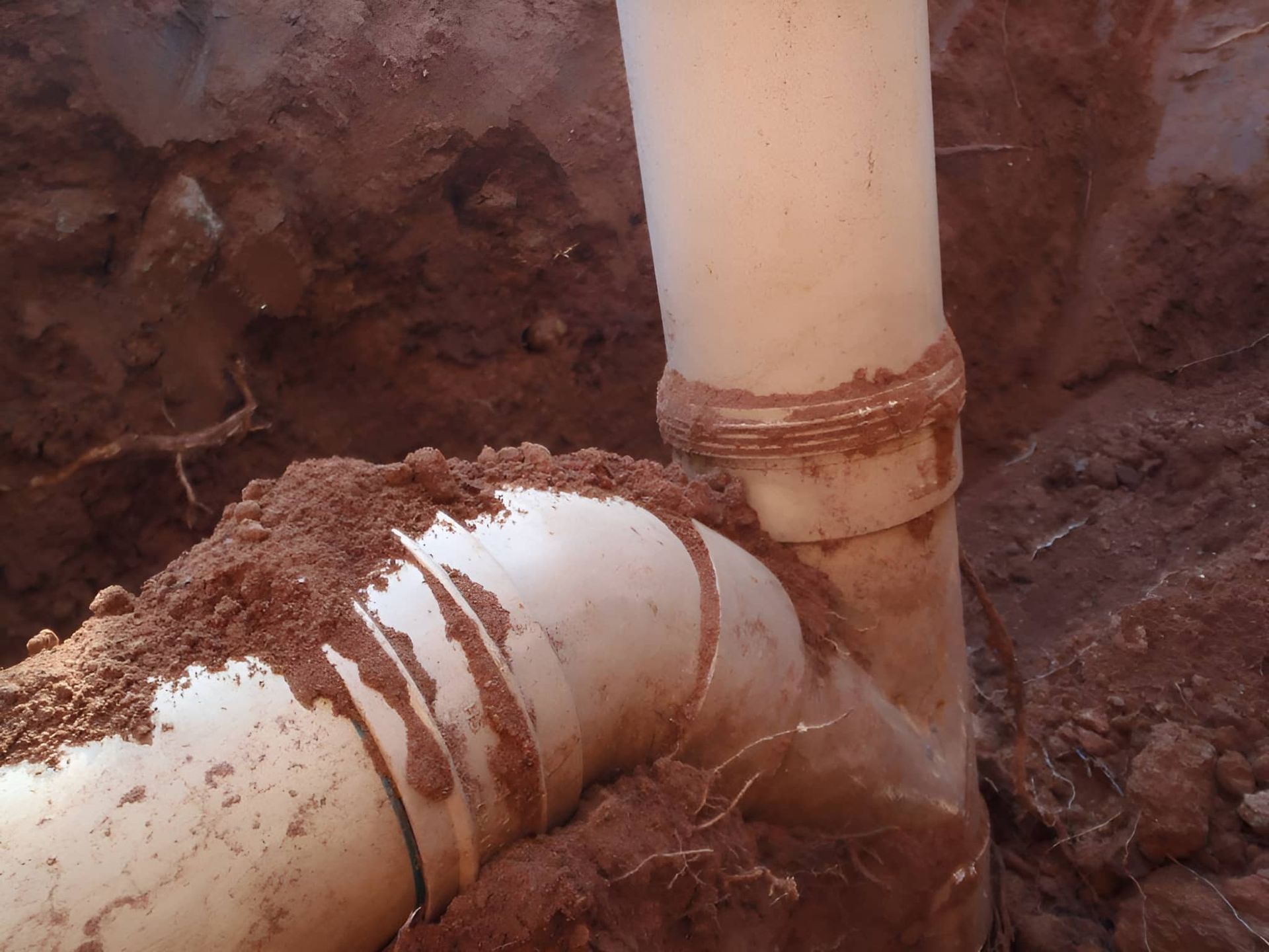 A Close Up Of A White Pipe In The Dirt — Araluen Plumbing In Braitling, NT