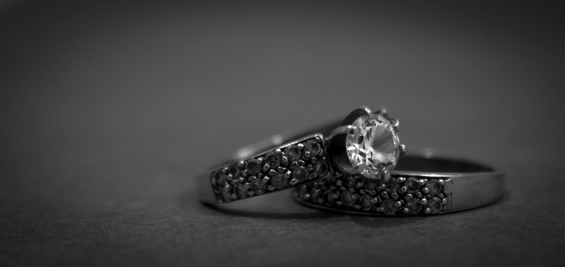 A black and white photo of two wedding rings on a table.