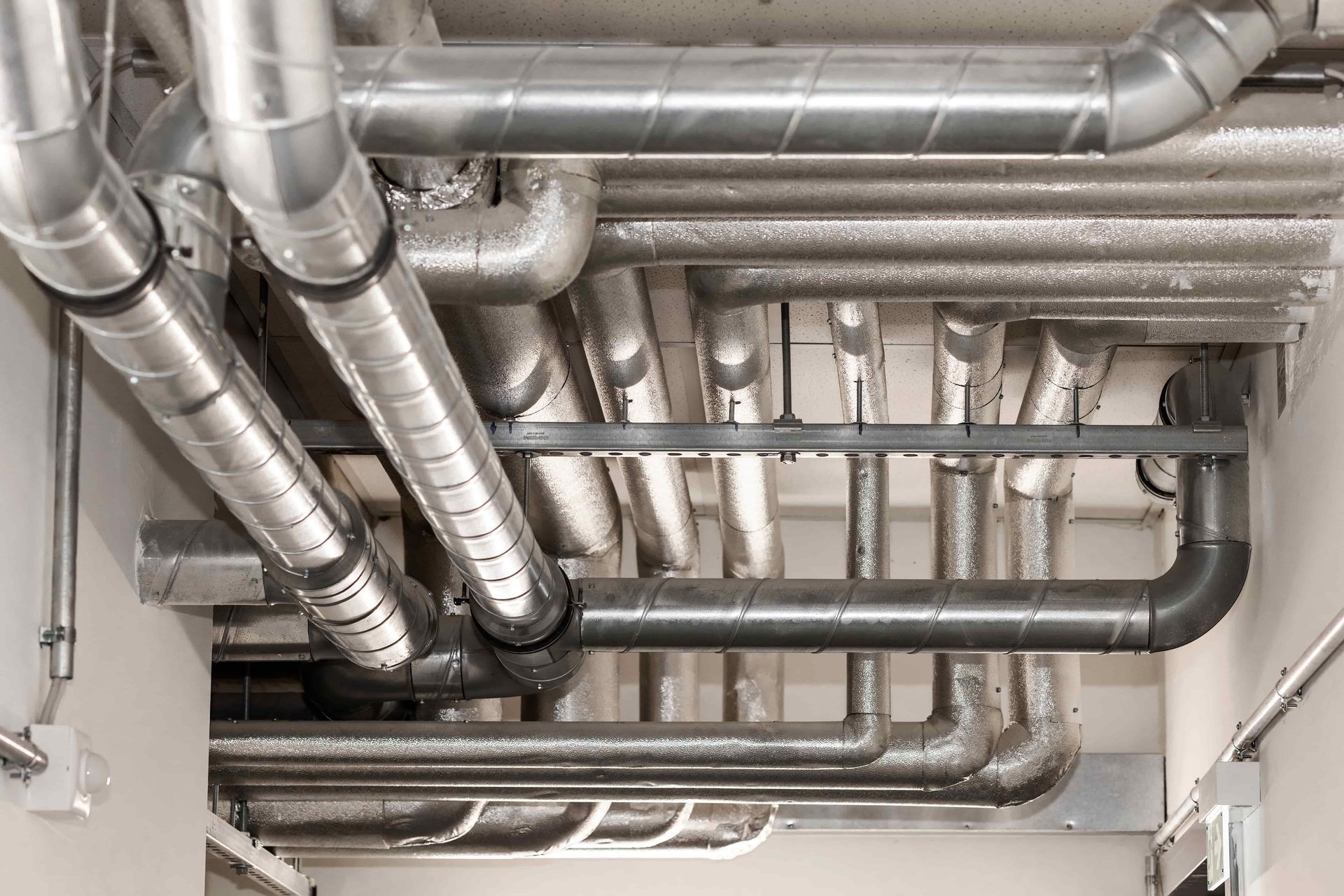 A bunch of pipes are hanging from the ceiling of a building.