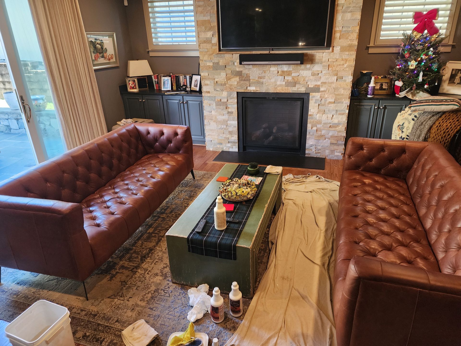 Cozy living room with two brown tufted sofas, stone fireplace, and Christmas tree decor
