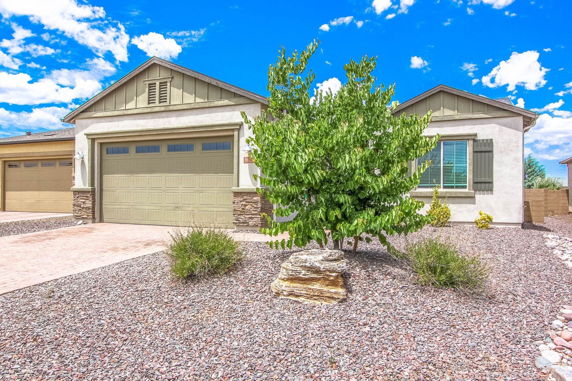 A house with a garage and a tree in front of it.