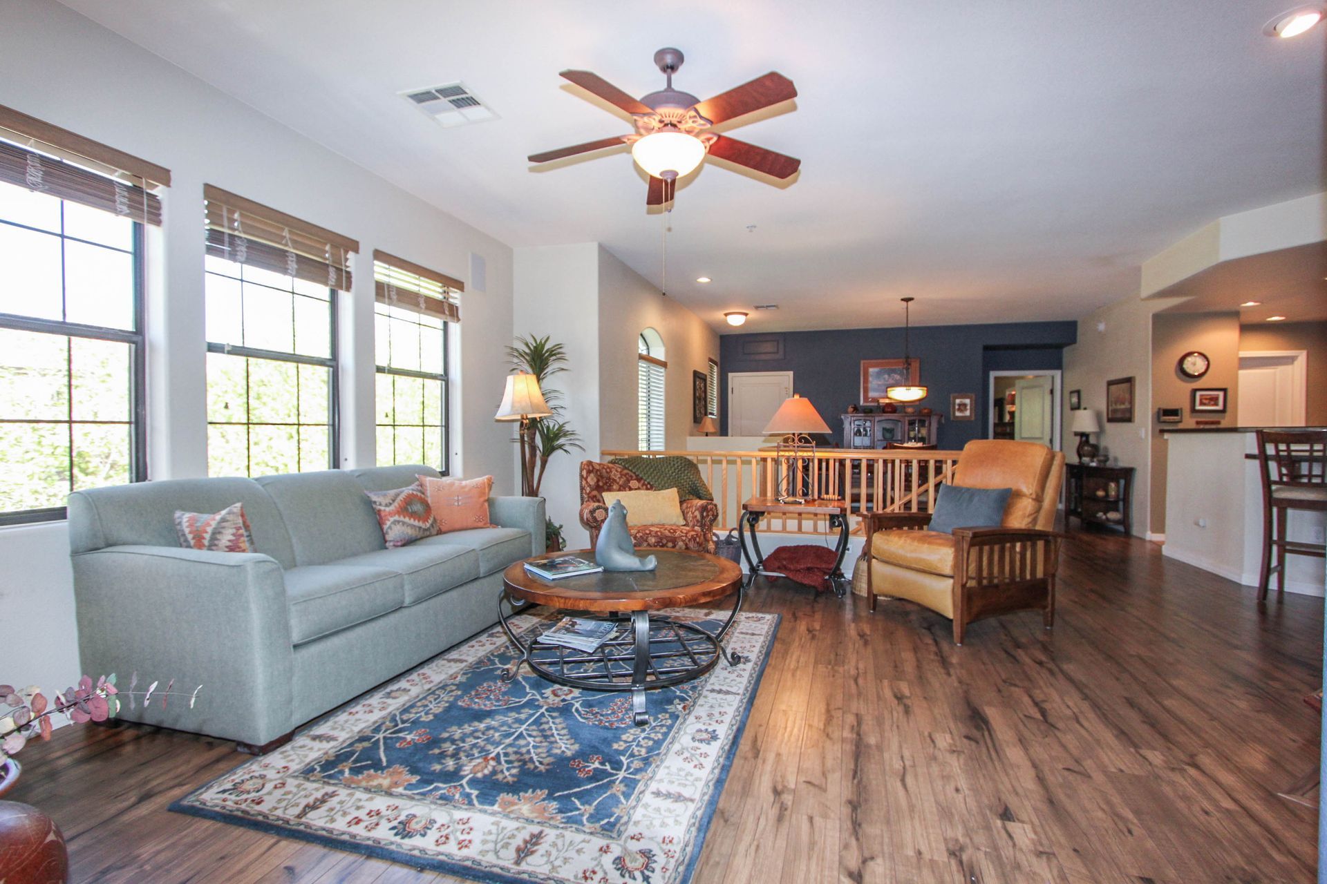 A living room with a couch , chairs , and a ceiling fan.