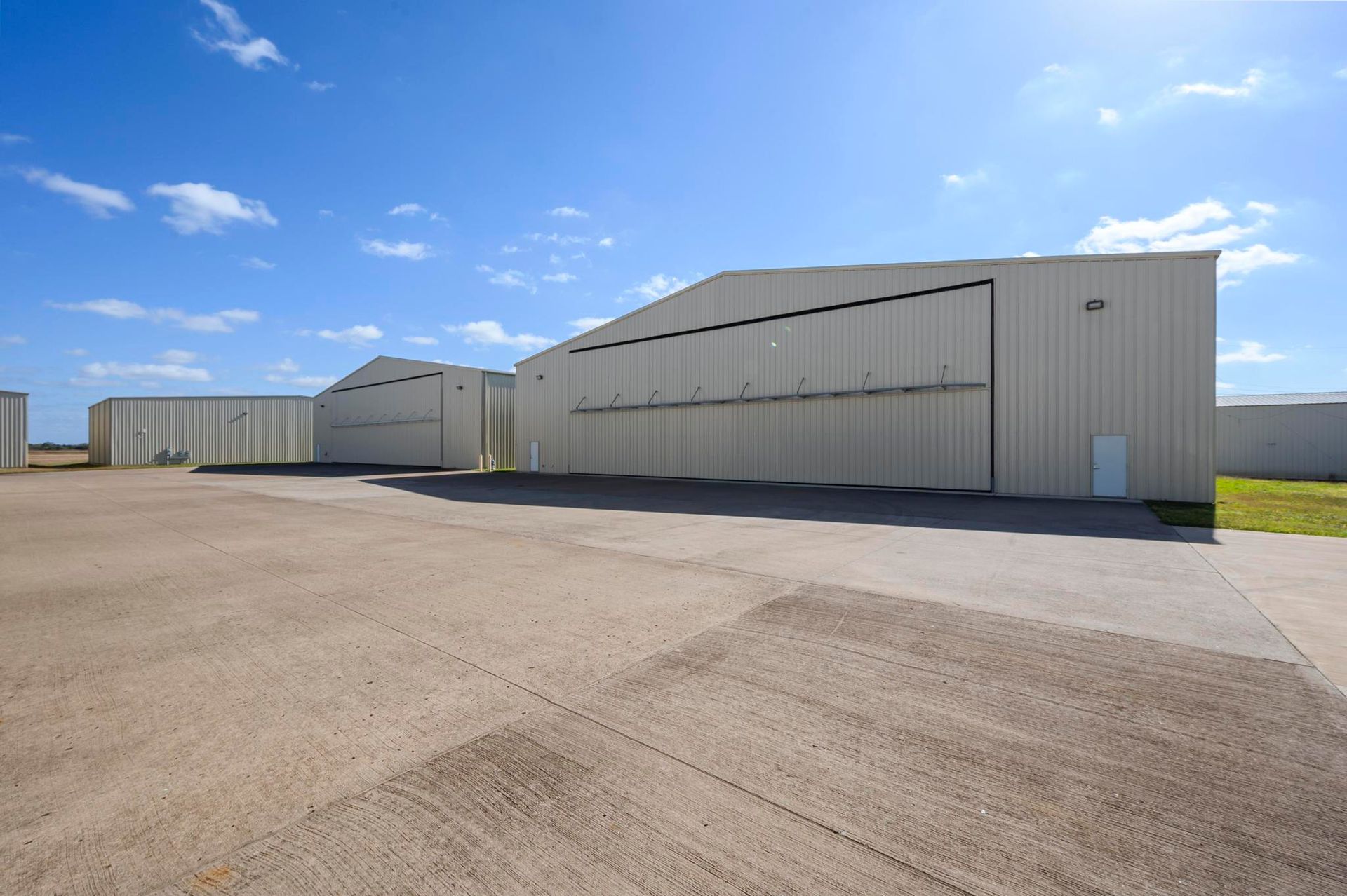 Large industrial warehouse buildings on a paved lot under a blue sky.