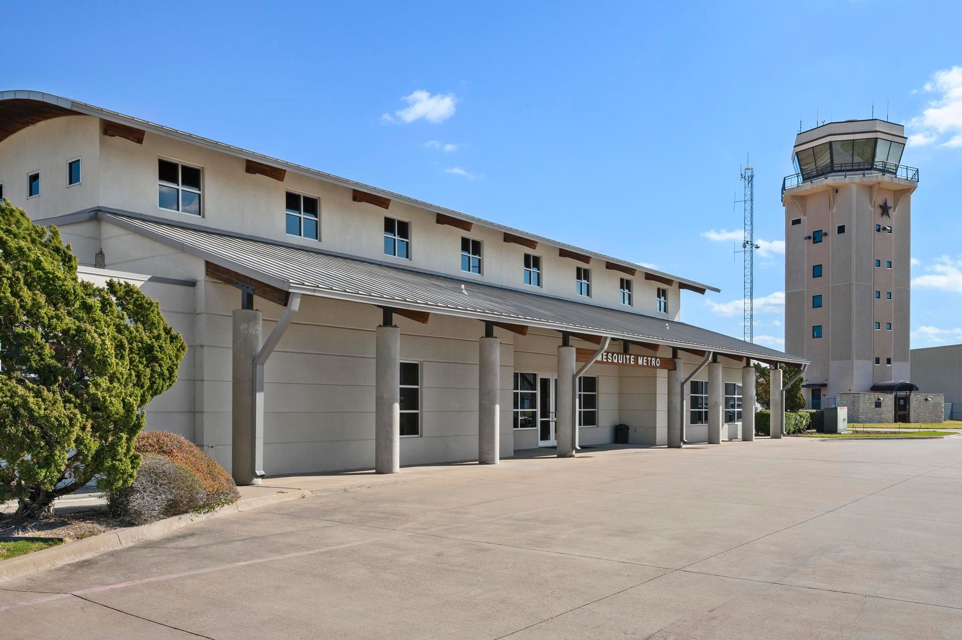 Airport terminal with garage doors and a tall control tower under a clear blue sky
