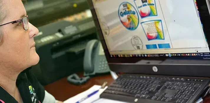 A woman is sitting at a desk looking at a computer screen.