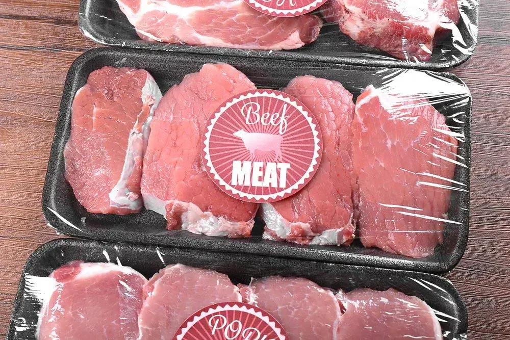 Three Trays of Beef Meat are Sitting on a Wooden Table — Aldine Printers in Bungalow, QLD
