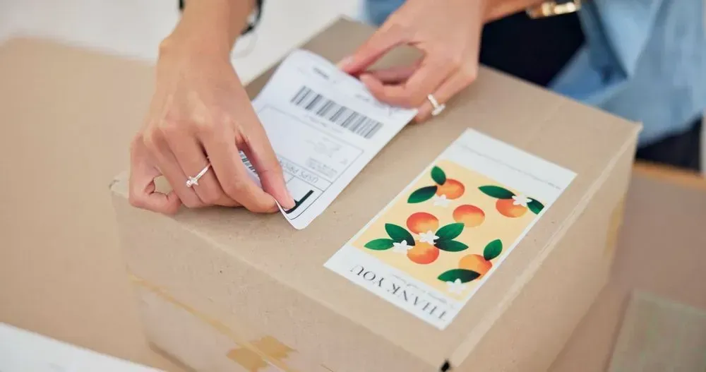 A Woman is Putting a Sticker on a Box — Aldine Printers in Bungalow, QLD