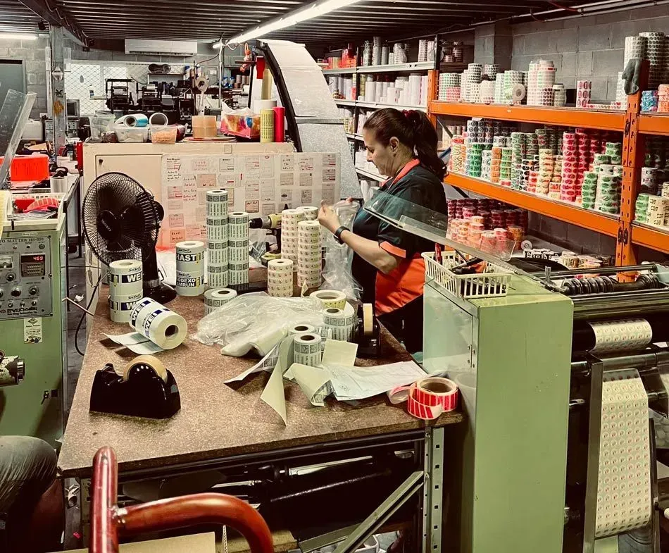A Woman is Standing in a Warehouse Surrounded by Rolls of Stickers — Aldine Printers in Bungalow, QLD