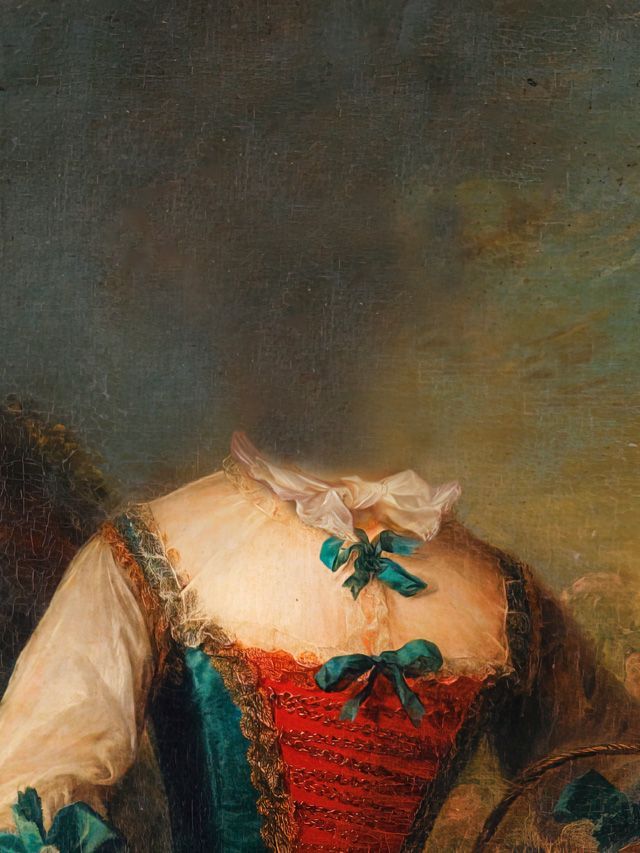 Close-up of a torso in a red and blue dress, white ruffled collar, bows.