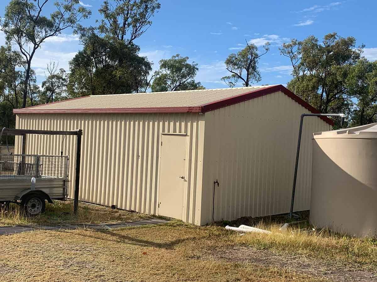 A Large Metal Building With a Red Roof — Ben McLennan Constructions in Port Macquarie, NSW