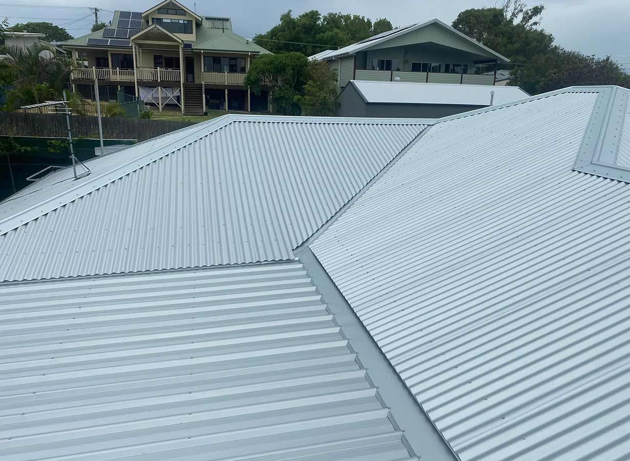 A White Corrugated Metal Roof With a House in the Background — Ben McLennan Constructions in Lismore, NSW