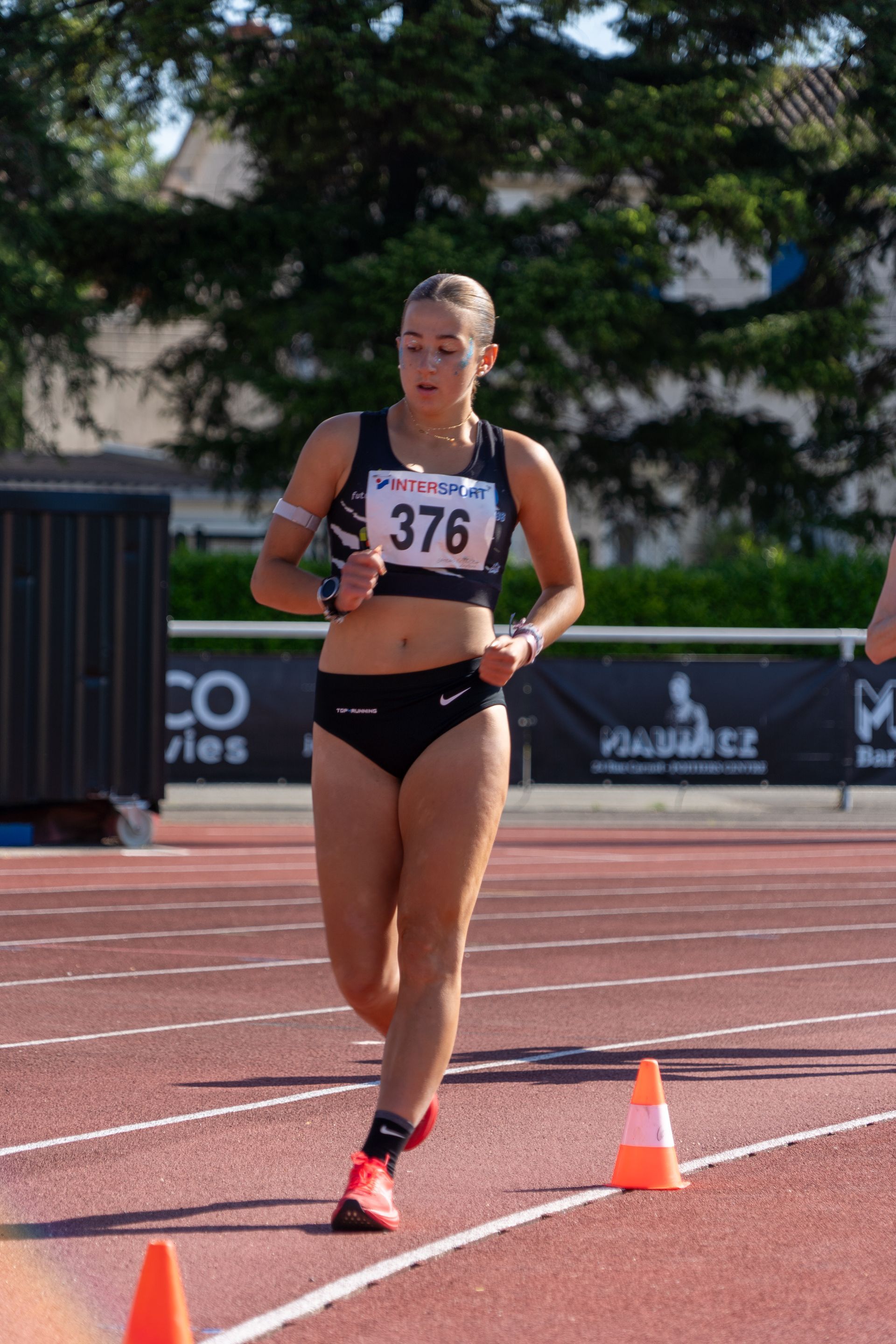 Athlète féminine, marchant sur une piste, portant une tenue de sport noire, concentrée. Daphné Gateau-Fernez.