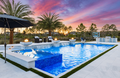 Fire bowls burning beside a custom pool at dusk